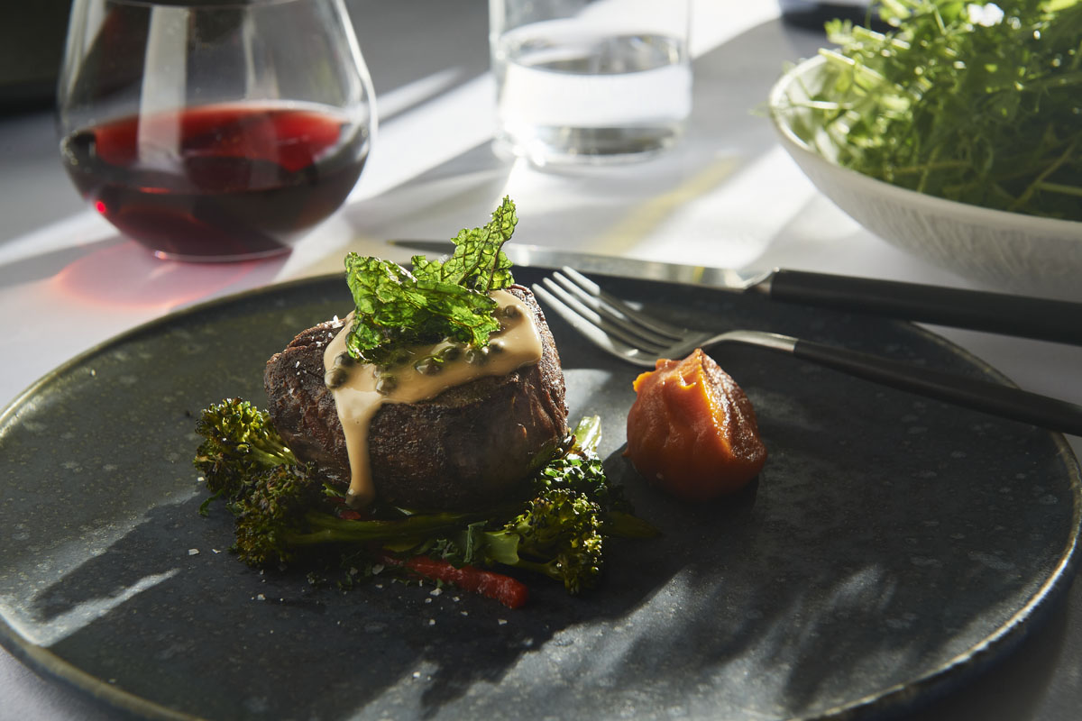 Autumn Winter event menu, Zinc at Fed Square, Main course, Roasted eye fillet, capsicum, charred broccolini, red wine pepper sauce presented on charcoal plate with red wine